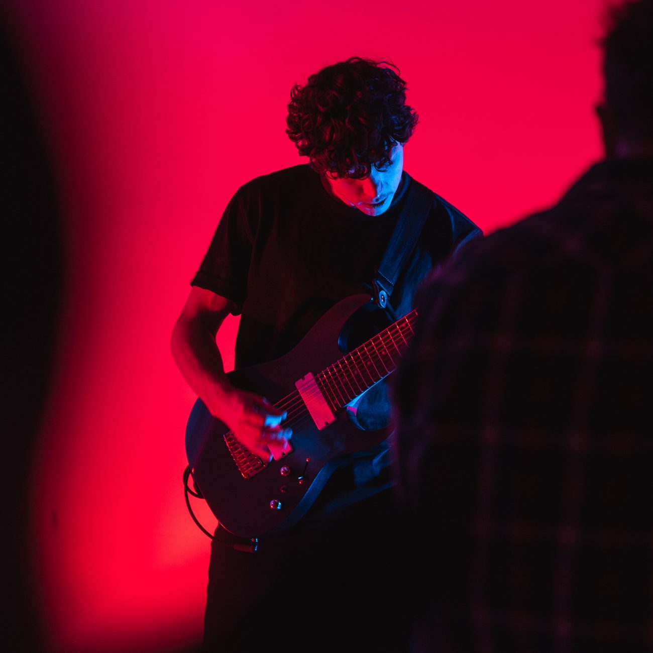 Gitarrist vor Roter Wand mit Kameramann im Vordergrund